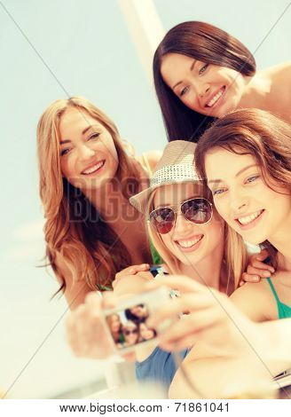 summer holidays and vacation concept - smiling girls taking photo in cafe on the beach