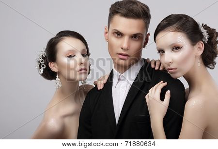 Love Triangle. Two Charming Women Hugging A Handsome Man