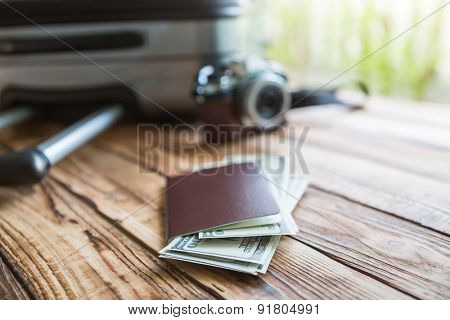 Blank passport and camera with US dollars on wood table