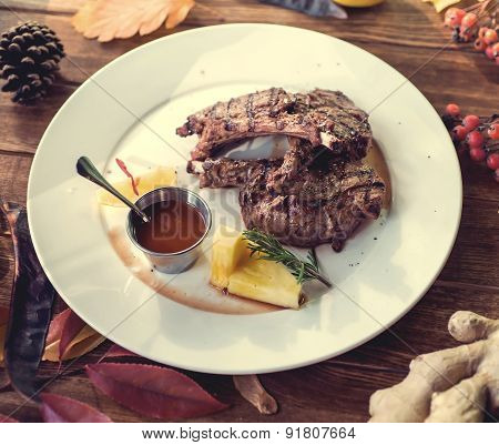 Close up of grilled pork ribs with lemon, sauce and rosmary. Selective Focus. Autumn concept decorat