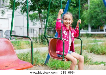 Cute little girl is playing in playground, outdoor shoot