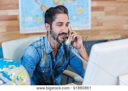 Smiling travel agent having phone call in the office