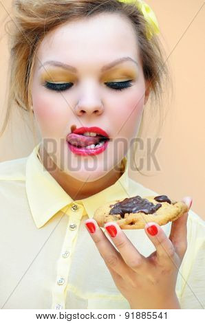 Trendy young woman is licking chocolate sauce off her lips.