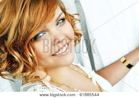 Stylish smiling young woman with curly short red hair.