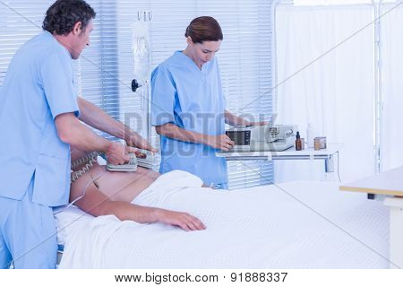 Medical team resuscitating a man with a defibrillator in hospital room