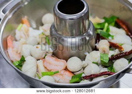 Fresh grilled shrimps with lemon on a pot of soup.