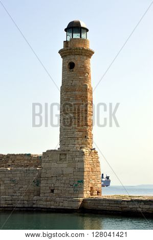 Marine lighthouse in a port of Crete with ramparts and the ocean.