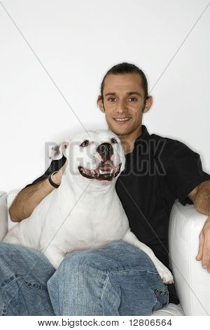 Młody dorosły kaukaski mężczyzna gospodarstwa biały pies Pit Bull na kolanach.