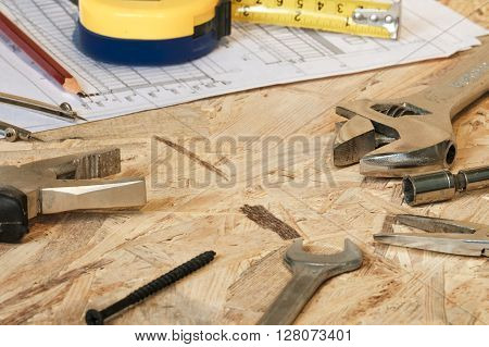 The working tools for construction and repair of house: tape measure (yardstick), wrench, screwdriver, pliers, spanner, screw, pencil. Photos with limited depth of field.