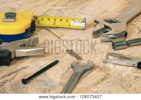 The working tools for construction and repair of house: tape measure (yardstick), wrench, screwdriver, pliers, spanner, screw. Photos with limited depth of field.