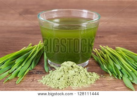 Heap of young powder barley barley grass and beverage on wooden background healthy nutrition and lifestyle body detox