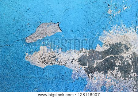 Blue painted grunge concrete wall. Weathered peeling paint texture. Blue weathered background. Bright blue paint texture cracked over time.