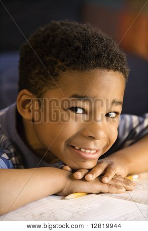 Retrato de menino sorridente com a cabeça nas mãos, com o livro em frente olhar viewer.
