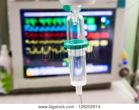 Intravenous drip with monitor on background