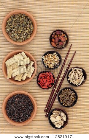 Chinese medicinal herb ingredients used in traditional herbal medicine over bamboo background. 