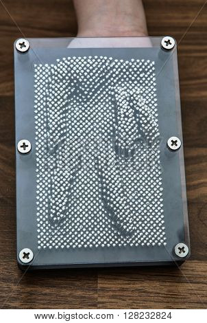 Retro pin board toy on the wooden background. Victory hand symbol. Silhouette of the hand.