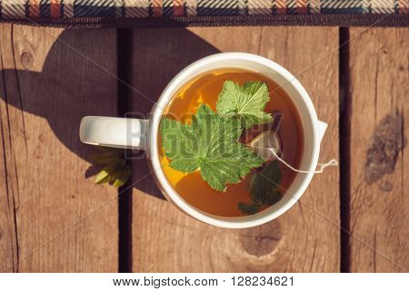 Top view of tea with currant leaf in white cup