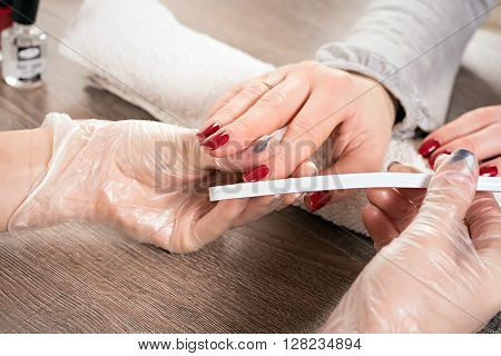 Young beautiful woman in a nail salon receiving a manicure by a professional beautician
