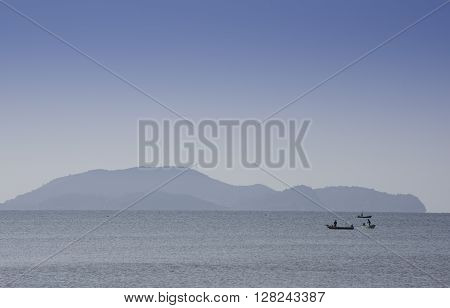 Silhouetted Fishing Boat Showing Misty Mountains Early Morning Sun.