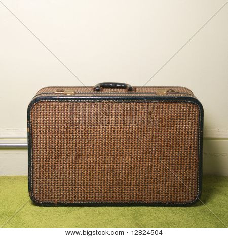 นิ่งของกระเป๋าเดินทางย้อนยุคสีน้ำตาลบนพรมสีเขียว