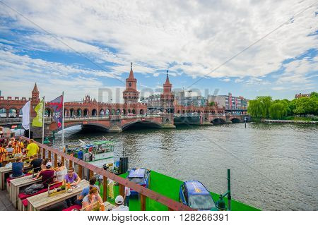 BERLIN, GERMANY - JUNE 06, 2015: Spree river cross under oberbaumbrucke, square on a side with excelent view. People eating and talking
