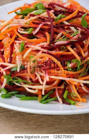 plate salad of shredded raw beets and carrots on celery root close-up