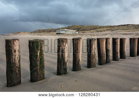 Breakwaters on the beach and a restaurant in the building dunes.
