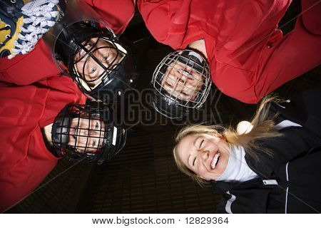 Low Angle weibliche Hockeyspieler in Huddle mit Trainer lächelnd.