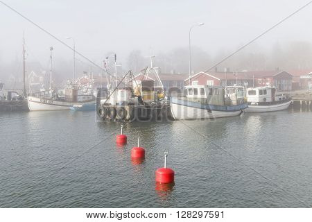 GRISSLEHAMN SWEDEN - MAY 01 2016: Small fishing boats in the harbor a foggy morning in Grisslehamn Sweden