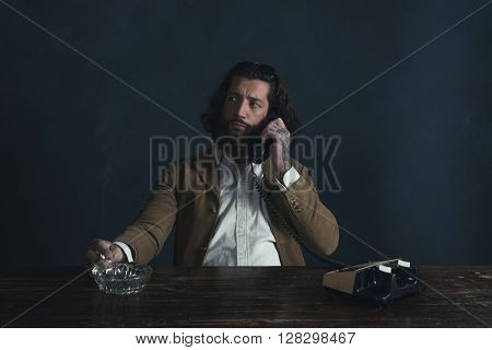 Retro 1970 Undercover Agent With Beard Calling Behind Desk While Smoking Cigarette.