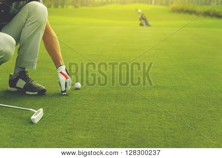 Male golfer marking ball position on the green. Focus on  pitchmark