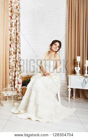 Wedding dress fashion. Beautiful young bride in vintage crochet shawl, shabby chic champagne color wedding dress. Rustic wedding dress at model, in decorated interior, studio shot, high key.