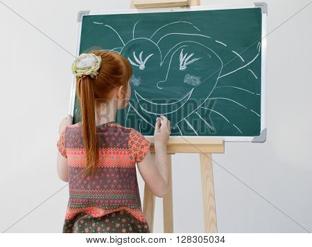The Little Red-haired Girl Draws On A School Board