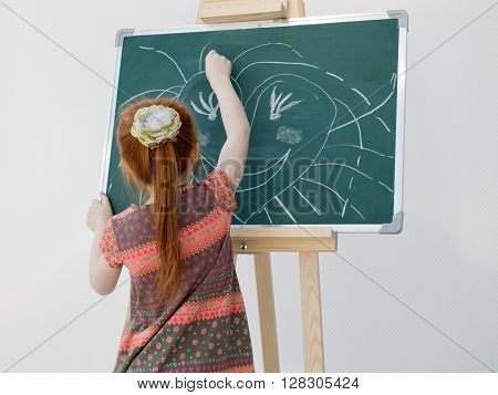 The Little Red-haired Girl Draws On A School Board
