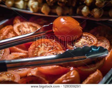 Fresh grilled red tomatoes on a salf service counter in a buffet restaurant in a hotel during breakfast service in the morning