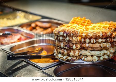 Hot counter containing warm breakfast items such as scrambled or fried tomatoes, waffles, bacon, sausages and others in a self service restaurant in a hotel
** Note: Visible grain at 100%, best at smaller sizes