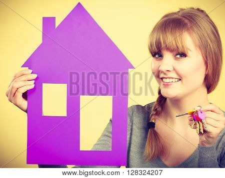 Ownership and property concept. Young blonde smiling female owner with bunch of colorful keys and house. Woman with key antry to her first own flat.