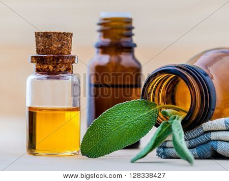 Bottle Of Essential Oil With  Fresh Sage Leaves Shallow Depth Of Field On Old Wooden Background.