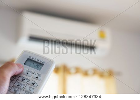 Close-up hand using remote control of air condition, selective focus