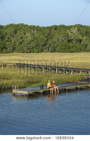 Luftfoto af to teenagedrenge fiskeri fra dock i sumpede lavlandet af Bald Head Island, North Caro