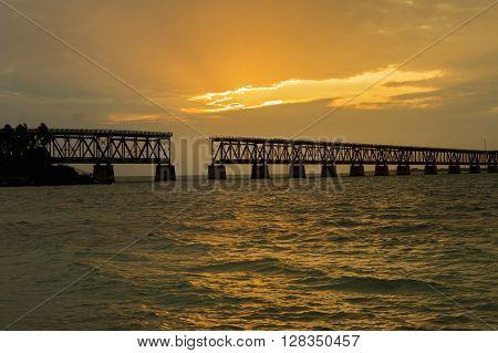 Beautiful colorful sunset or sunrise with broken bridge and sun rays spreading through purple clouds. Taken at Bahia Honda state park in the Florida Keys.