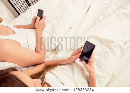 Close Up Photo Of Young Couple Lyng In Bed With Mobile Phones
