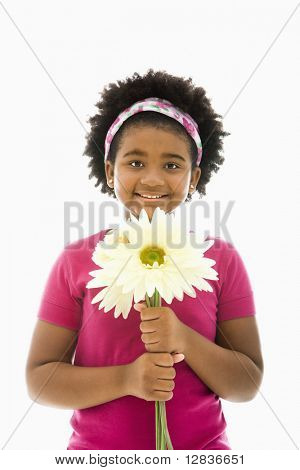 African American girl innehar stora Gerbera Daisies leende på viewer.