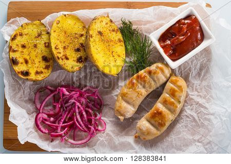 macro meat kupaty with fries and greens on white plate. potato