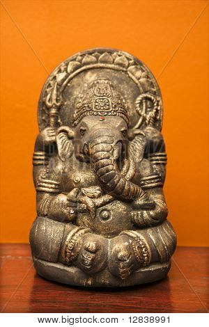 Estatua de elefante hindú Ganesha contra pared naranja.