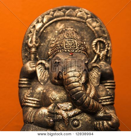 Standbeeld van hindoe olifant Ganesha tegen oranje muur.