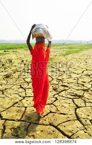 Women carrying baskets on dry ground, India