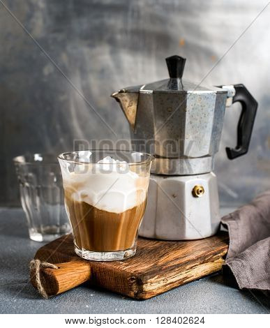 Glass of coffee with ice cream on rustic wooden board and steel Italian Moka pot. Metal background, selectibe focus
