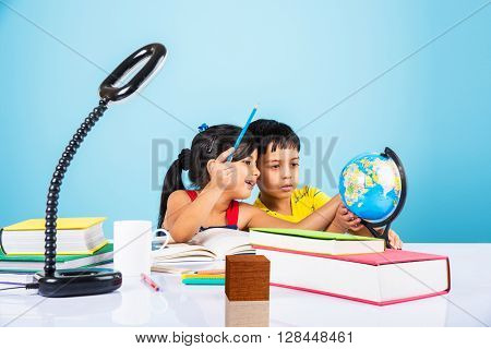 indian boy and girl studying with globe on study table, asian kids studying, indian kids studying geography, kids doing homework or home work, two kids studying on table