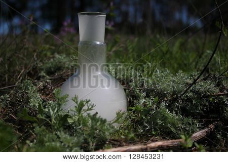 retort with smoke in a green grass